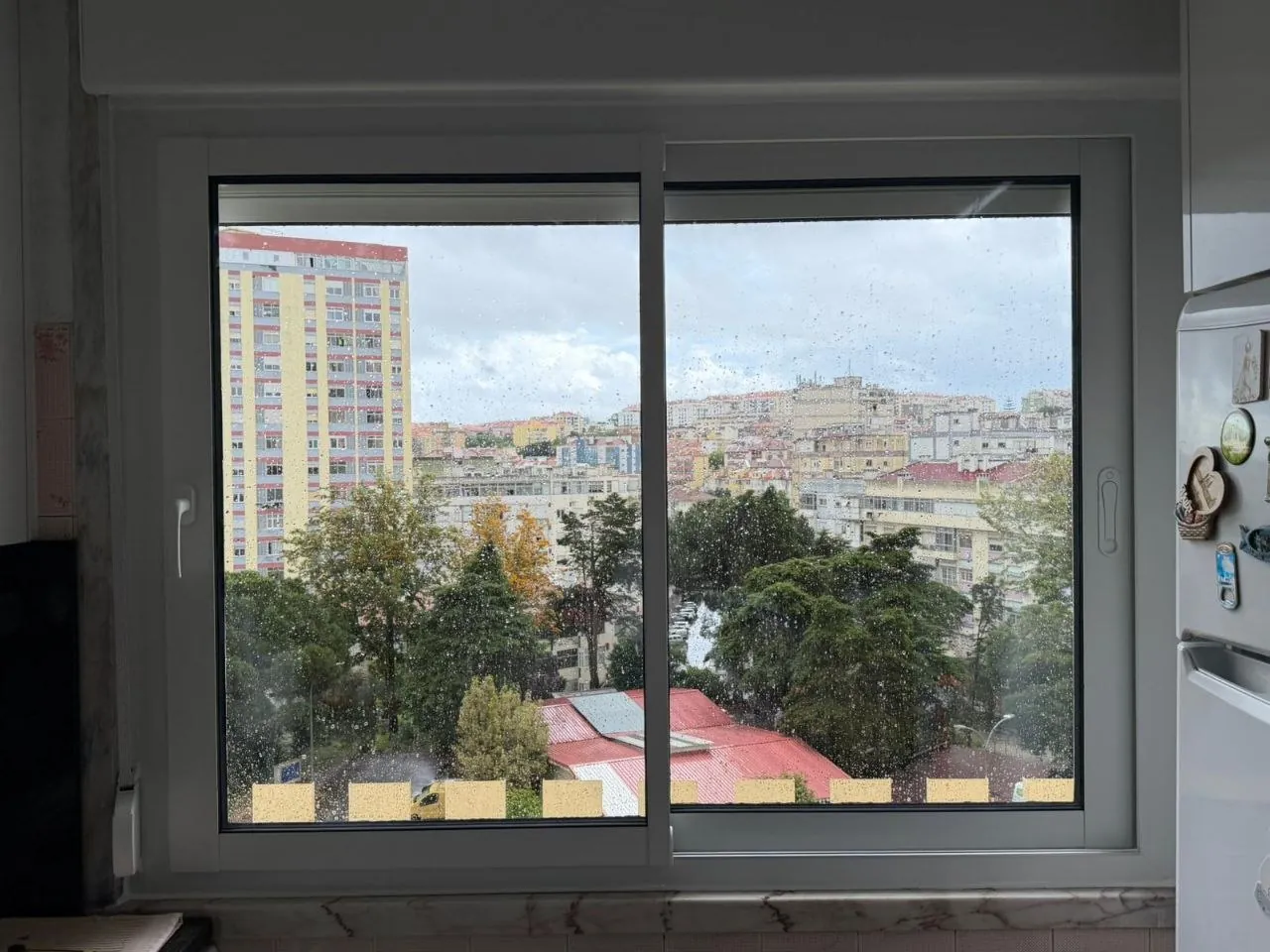 Janela de correr em alumínio numa cozinha, com vista sobre a cidade