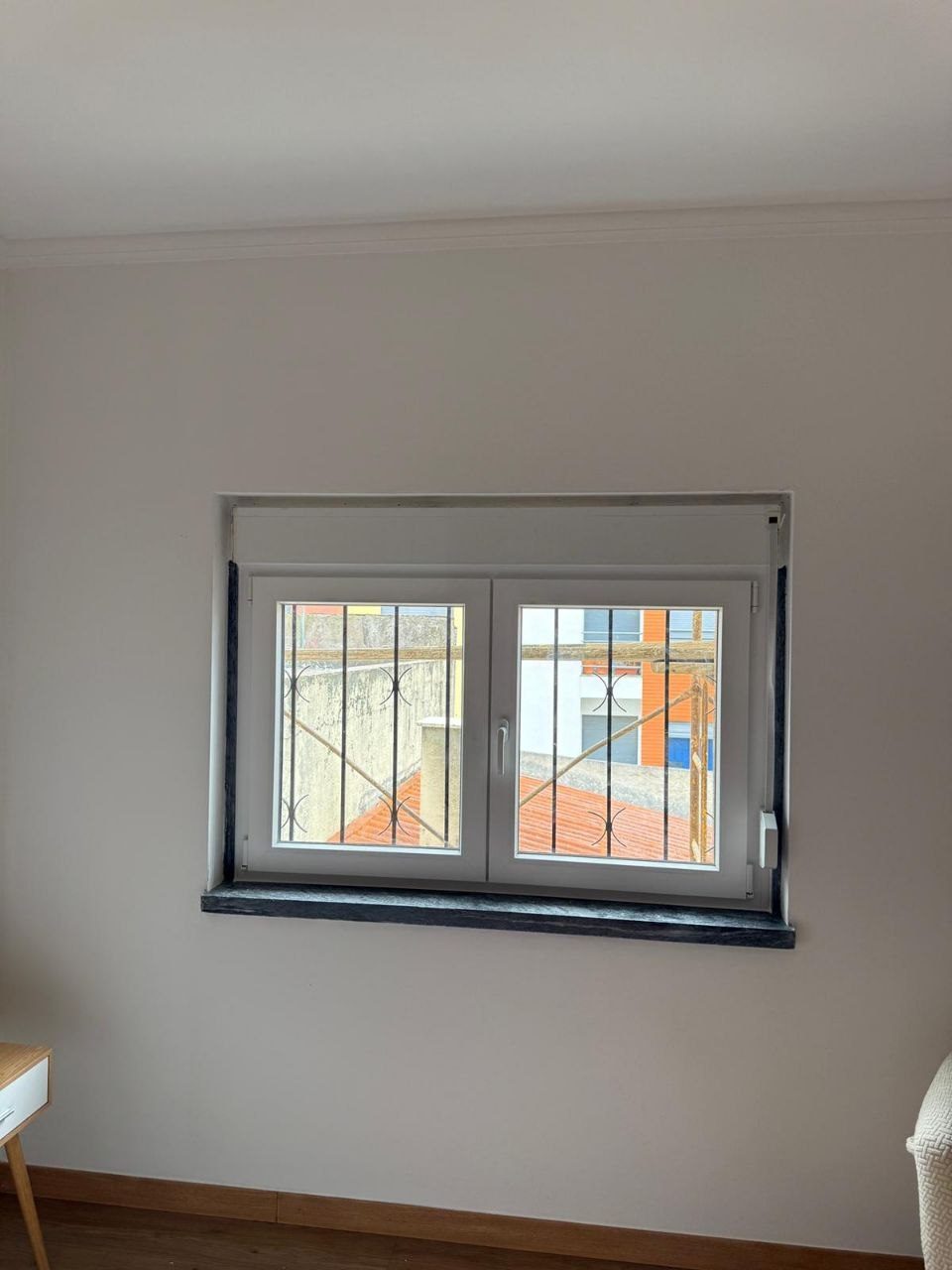 Janela de duas folhas em PVC branco, com as grades exteriores existentes mantidas