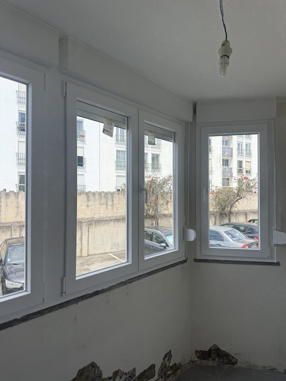 Marquise de canto fechada com janelas de PVC branco, com as paredes ainda em obra